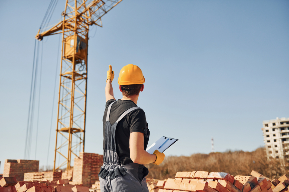 Promoteurs immobiliers à Rennes – Ouvrier constructeur sur un chantier immobilier fait un signe de la main à une grue. 