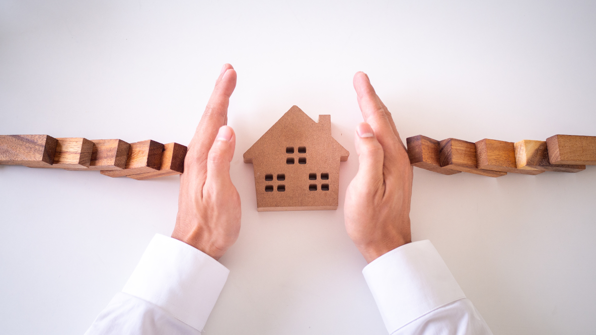 louer son appartement par agence immobilière - Mains sécurisant une maison en bois et symbolisant les garanties constructeur