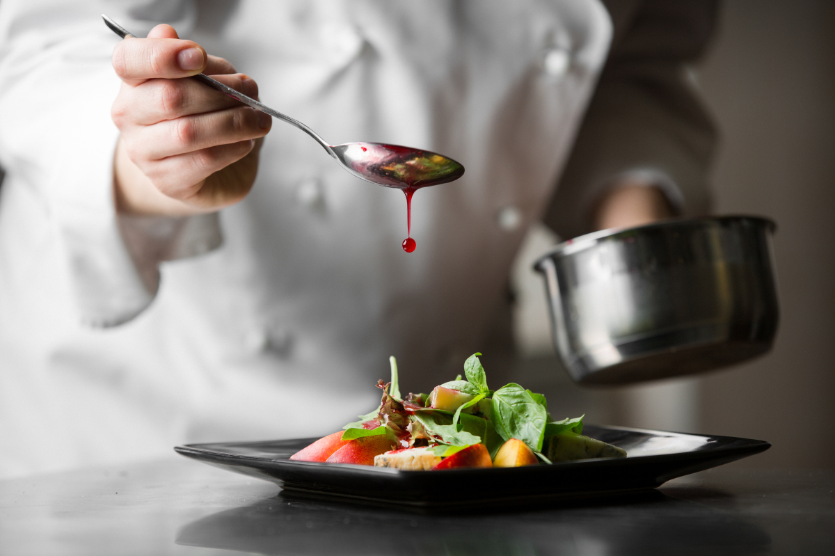 Legendre Immobilier – Cuisinier verse de la sauce sur une assiette