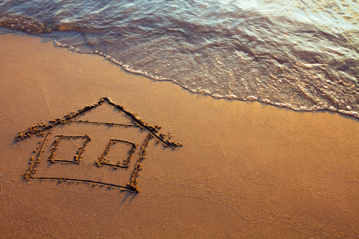 Fiscalité à Rennes – Maison dessinée sur le sable au coucher du soleil