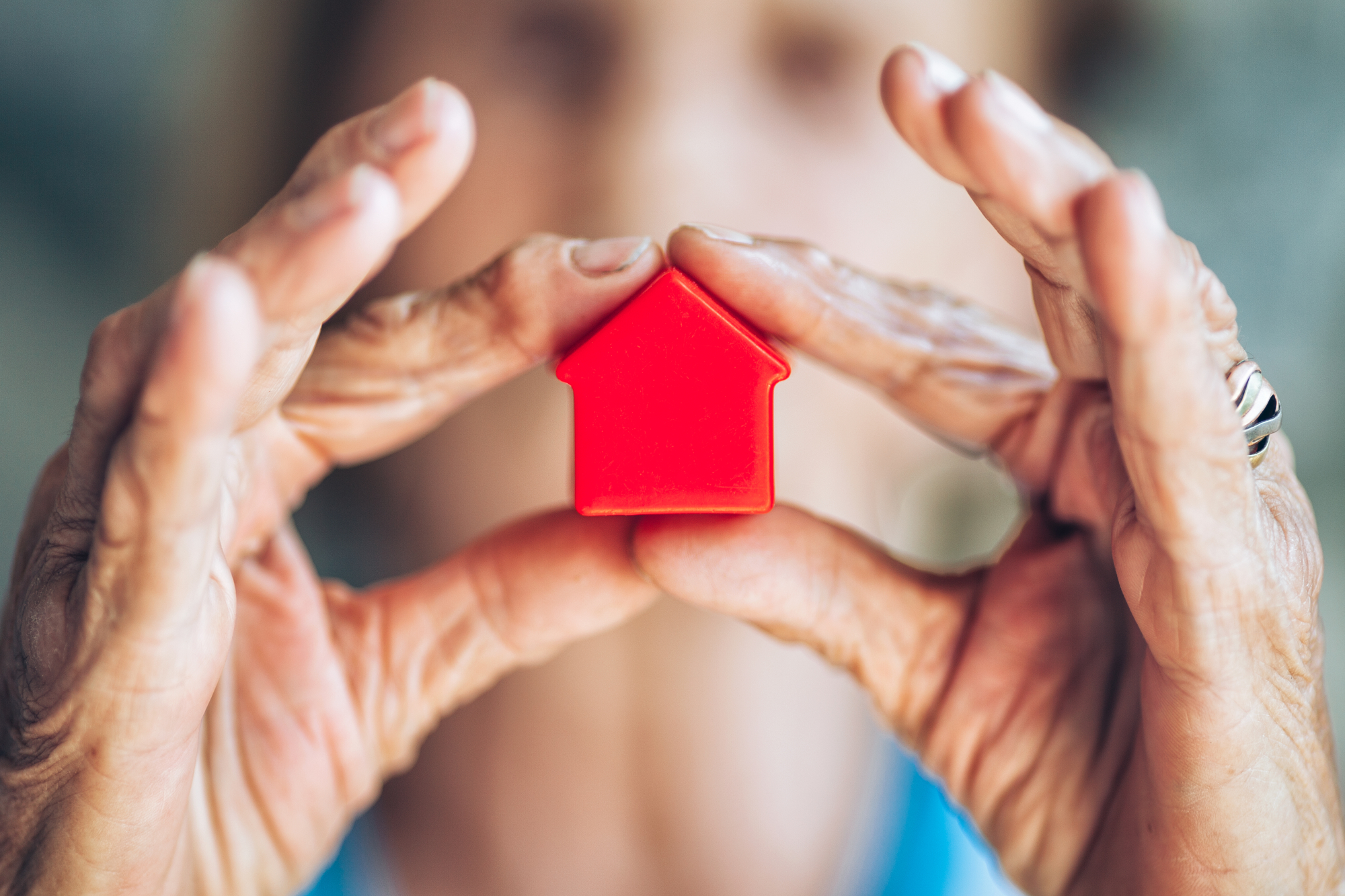 dame âgée tient figurine maison dans ses mains