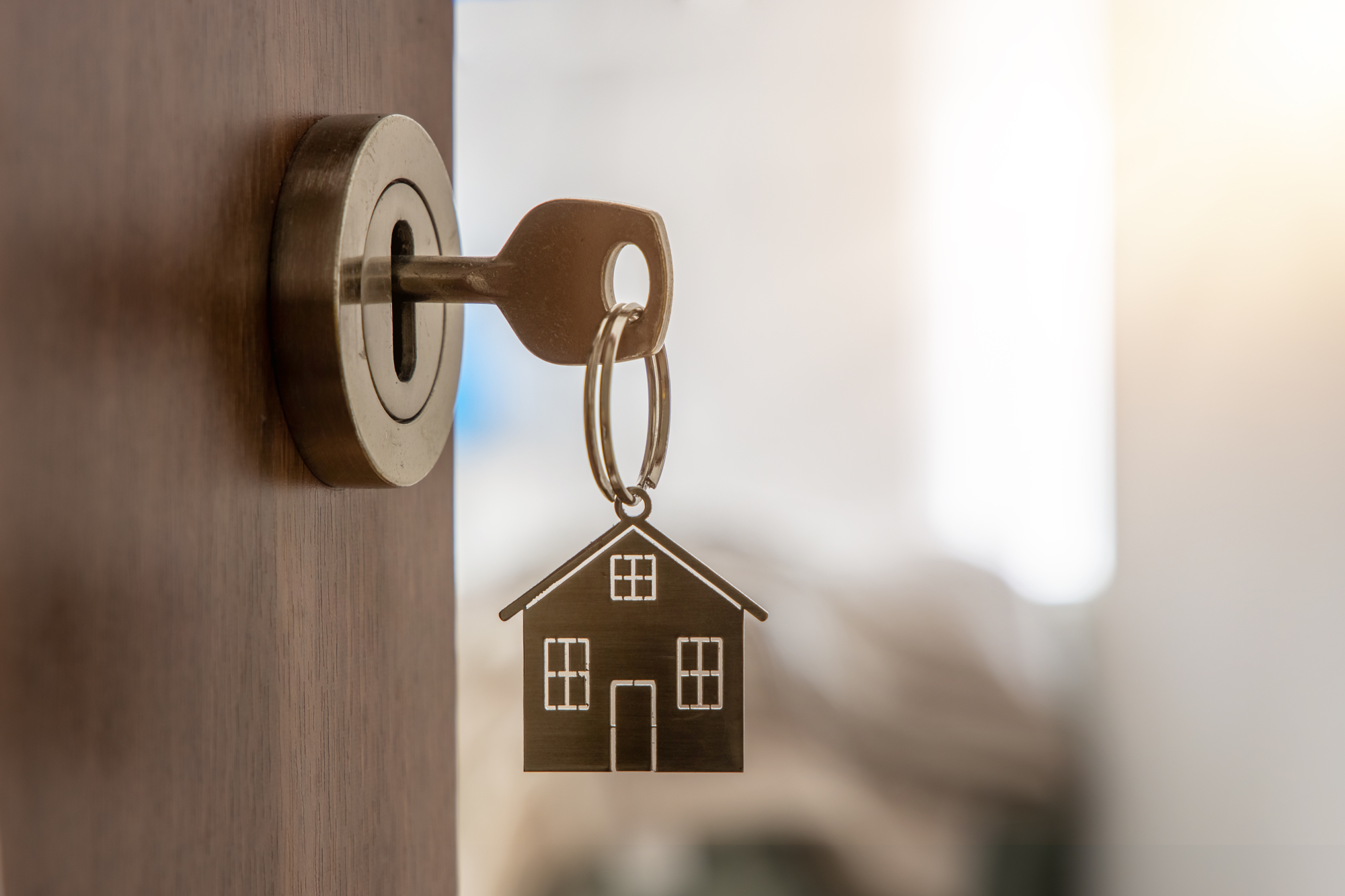 Clé sur une porte ouverte avec porte-clé en forme de maison