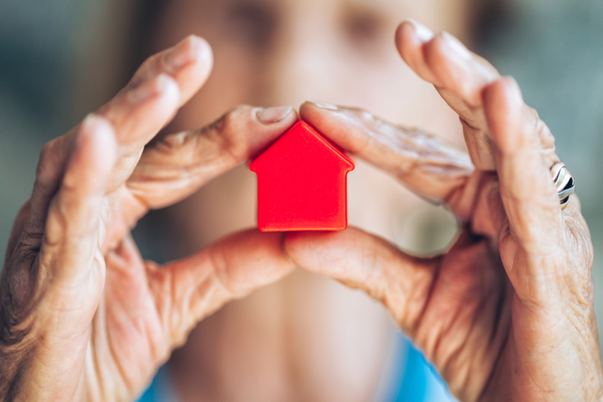 Personne âgée tenant dans ses mains une petite maison rouge - Dispositif Censi-Bouvard