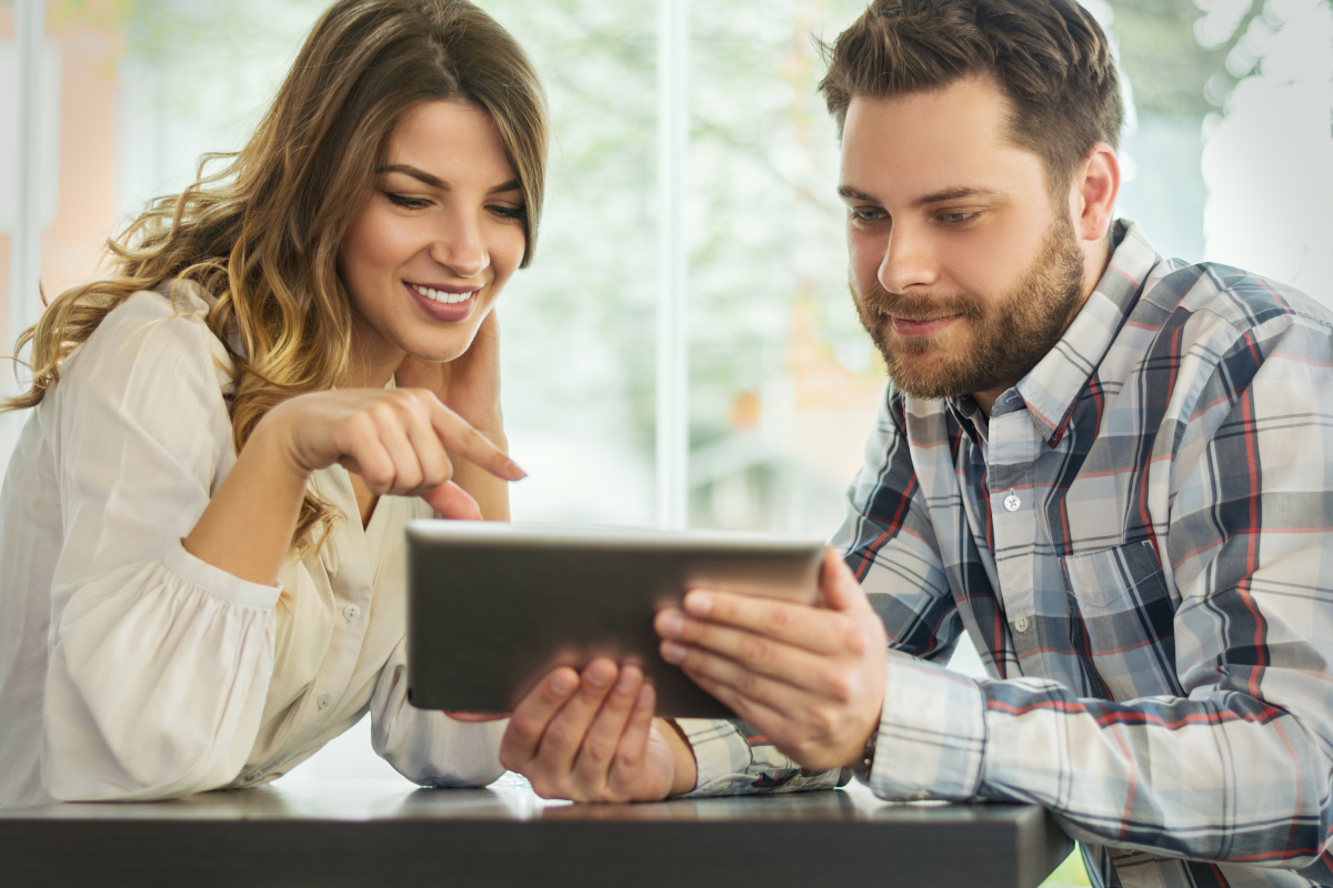 Une jeune couple consulte l'offre immobilière sur une tablette en visioconférence