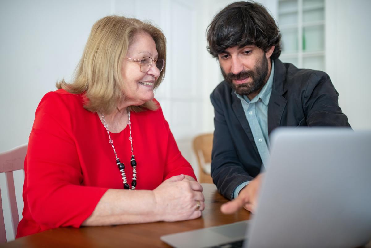 Prêt immobilier après 60 ans – Une femme âgée et son conseiller bancaire discutent des taux de crédit et d’assurance pour un projet d’achat immobilier