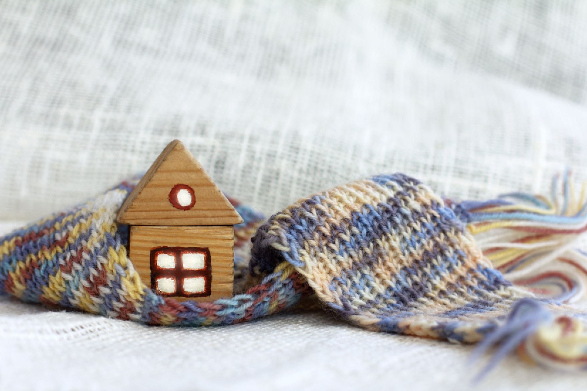 Une maison miniature en bois entourée d'une écharpe en laine