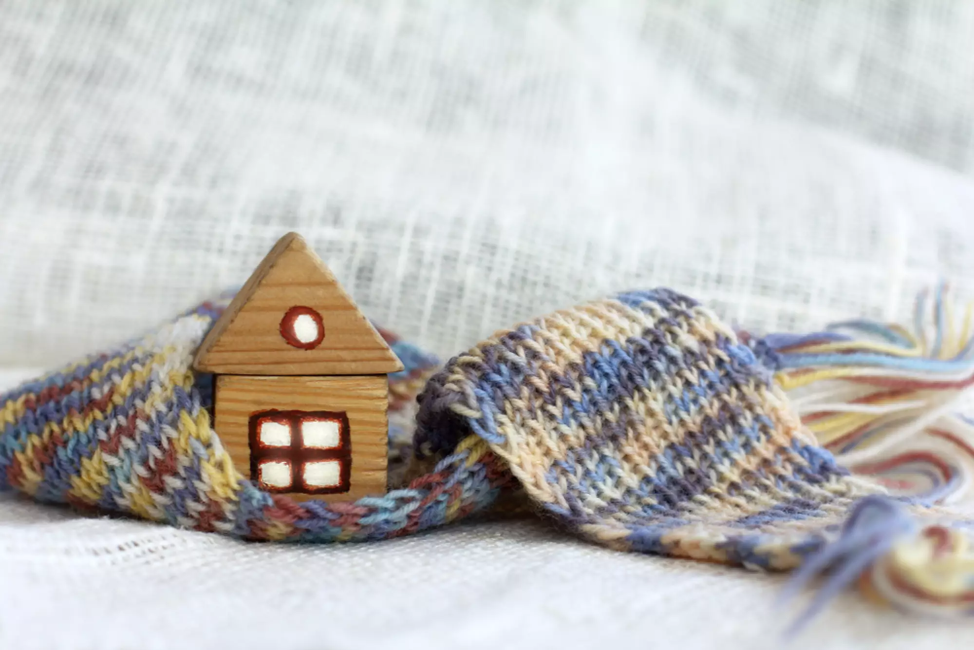 Une maison miniature en bois entourée d'une écharpe en laine