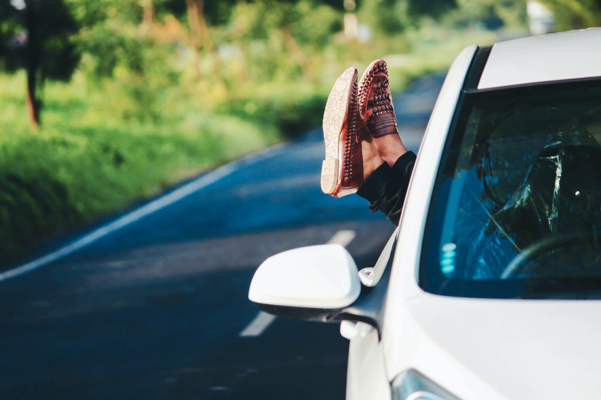 Une personne pose ses jambes sur la vitre de la voiture