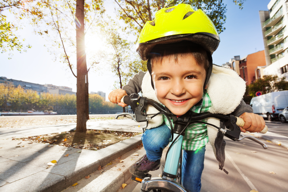 un enfant à vélo sur un boulevard avec un casque jaune fluo
