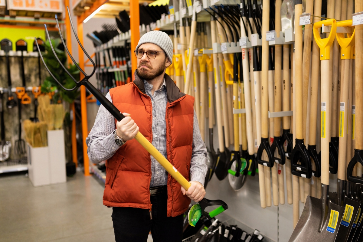 un homme soulève une fourche dans un magasin d’outillage