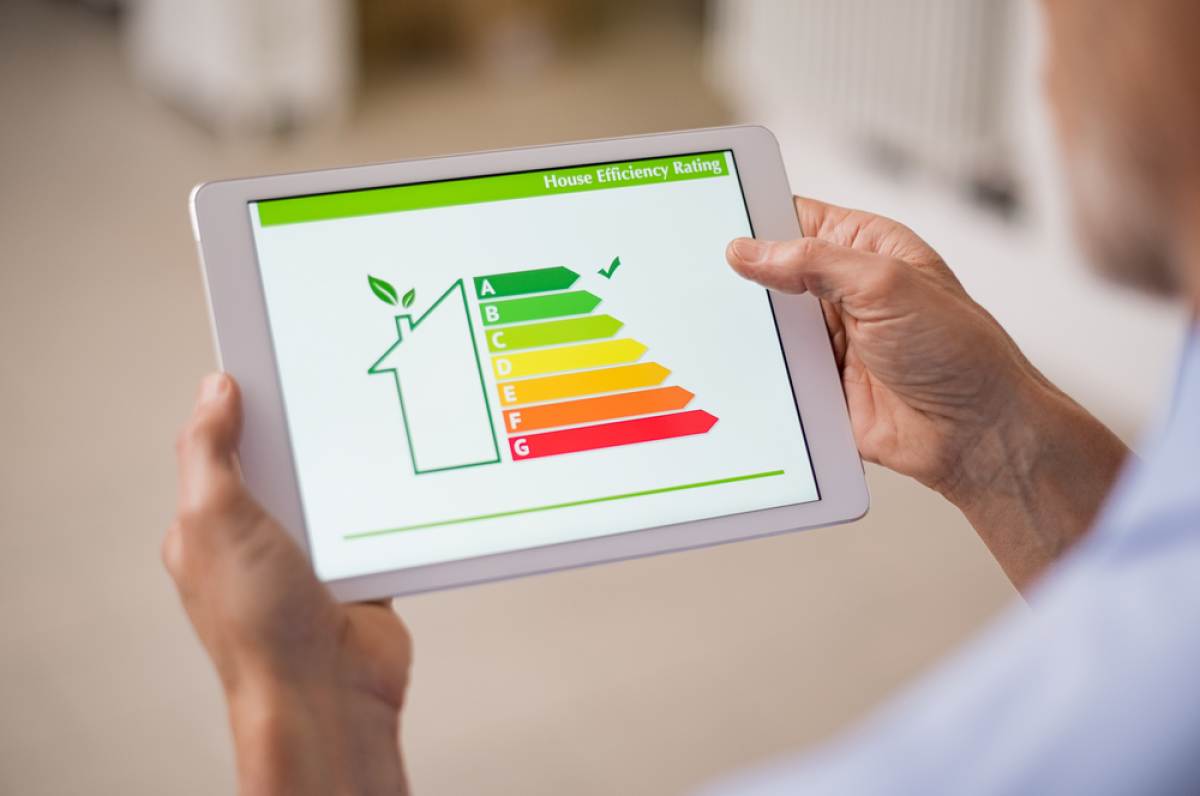 deux mains d’homme tiennent une tablette avec une infographie de DPE A