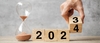 Un sablier et des cubes en bois avec la date 2023 inscrite et remplacée par 2024