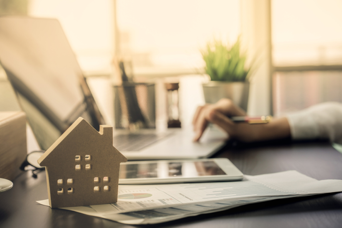 Certains obstacles se dressent sur la route du LLI logement locatif intermédiaire – une personne travaille sur un bureau avec une petite maison en bois posée