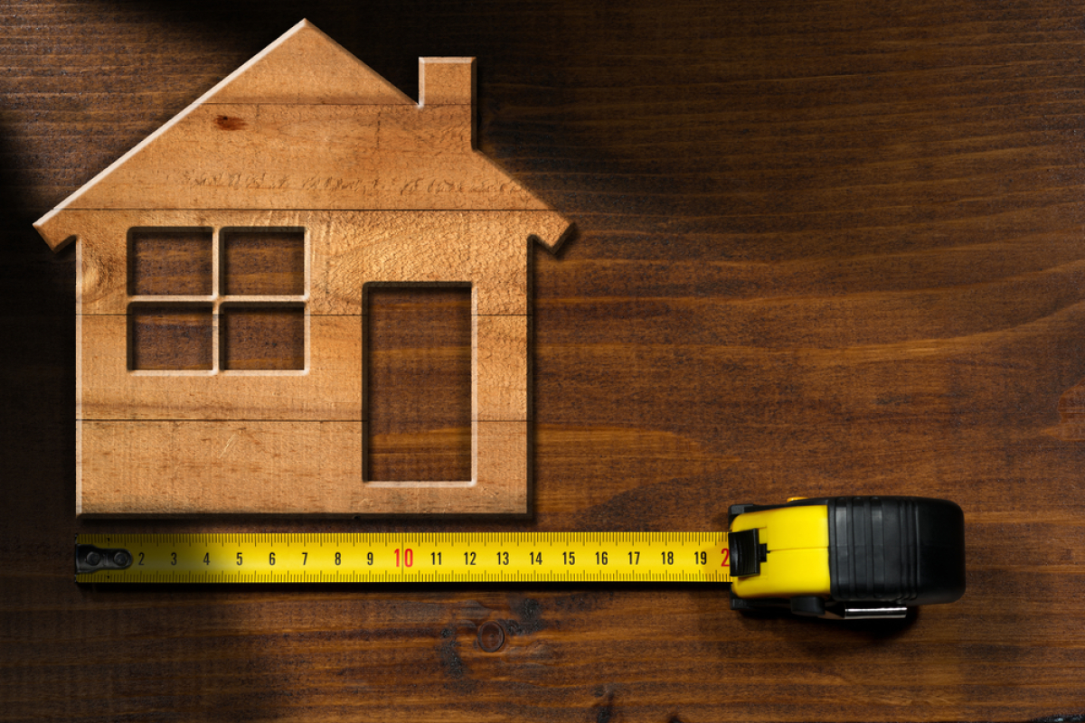 surface habitable et surface utile – une petite maison en bois et un mètre déroulé en-dessous