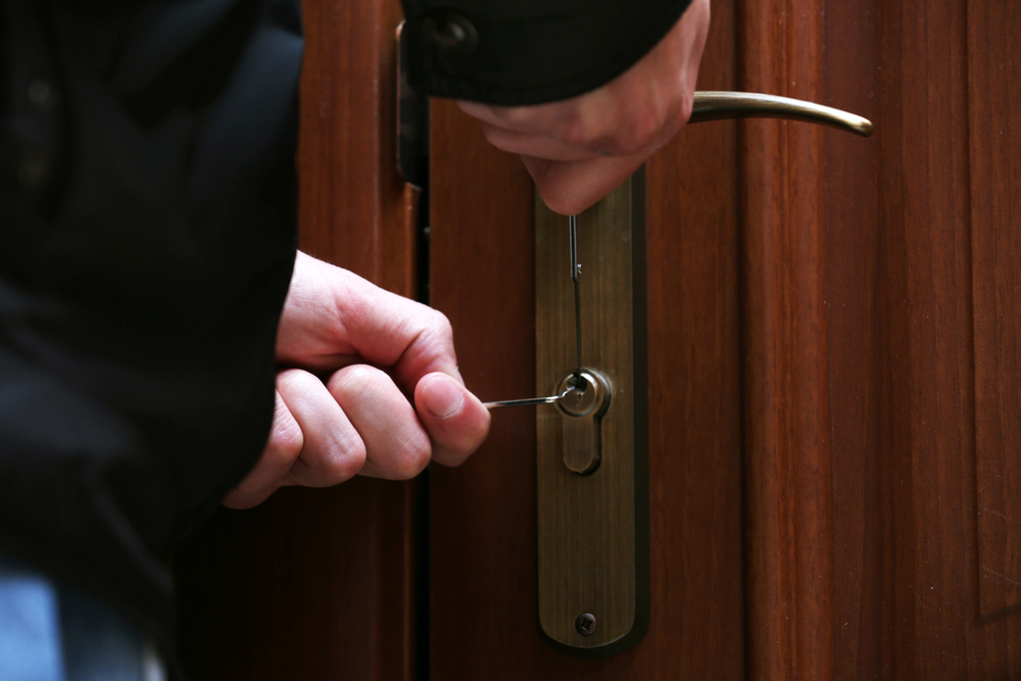 Une personne crochète la serrure d'une porte d'entrée