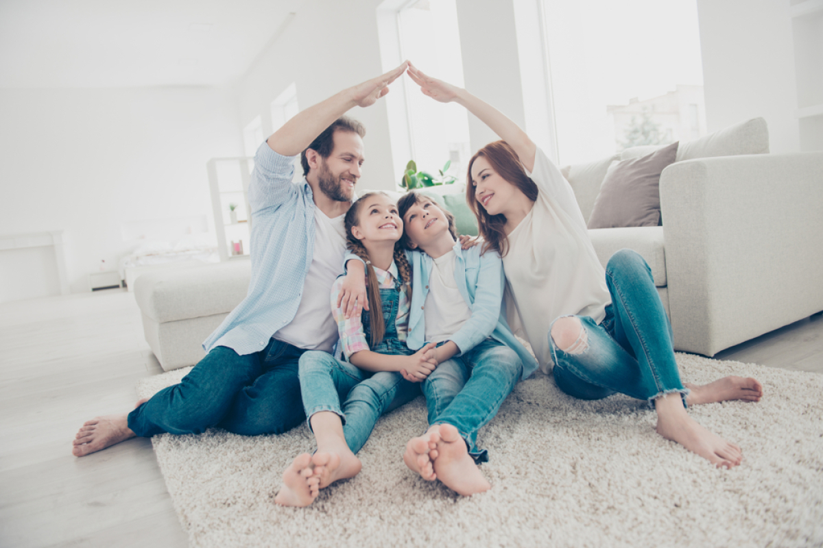 des parents forment une maison avec leurs bras au-dessus de deux enfants