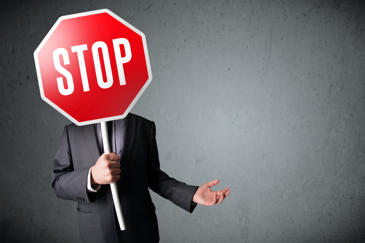 un homme en costume tient un panneau stop devant son visage