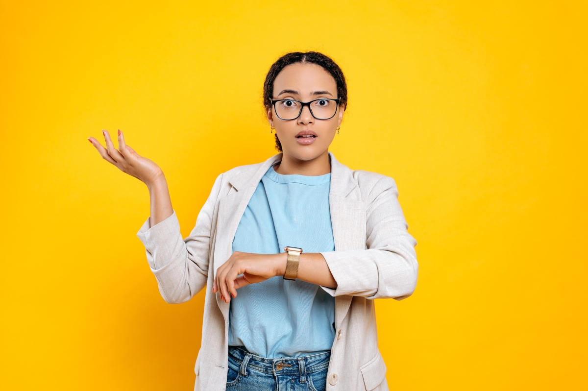 une femme à l'expression interrogatrice regarde sa montre 