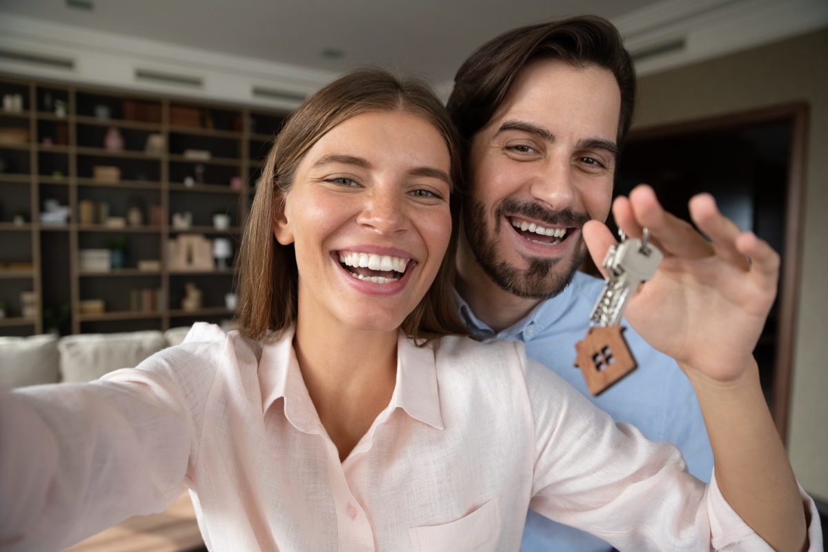 un couple souriant tenant un trousseau de clés
