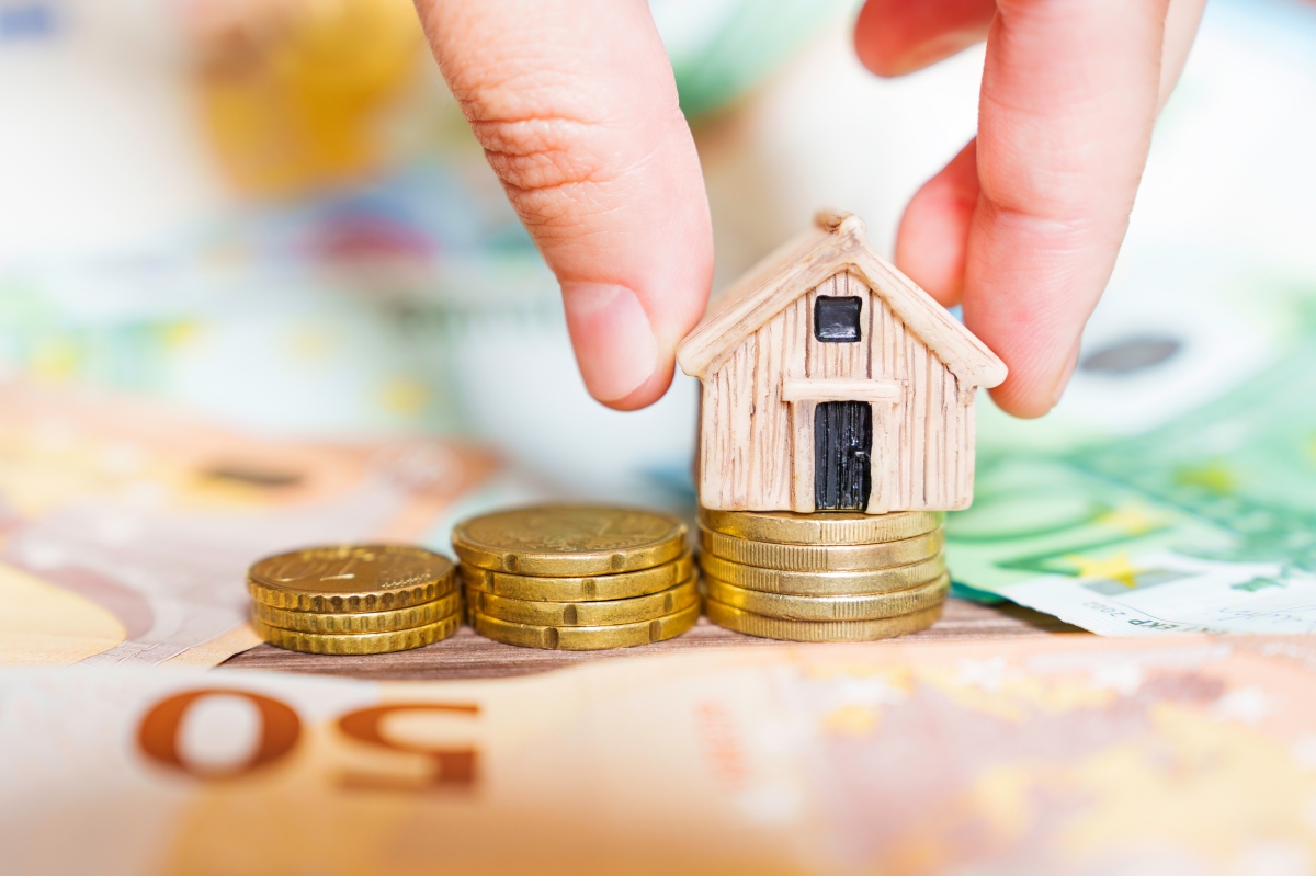 Baisse des prix immobilier Rennes — Une maison miniature posée sur des billets et des pièces de monnaie