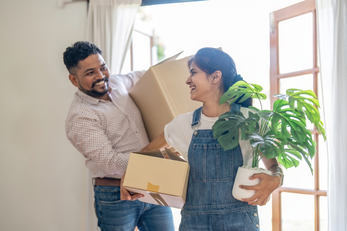 un couple souriant emménage dans un logement