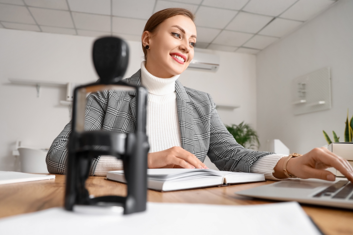 une femme souriante au bureau avec un tampon au premier plan