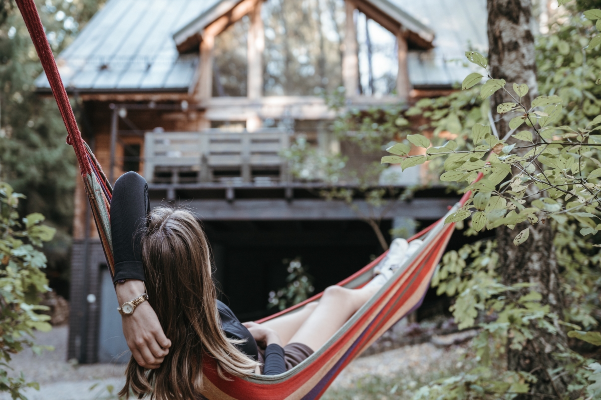 une femme dans un hamac devant un chalet de bois