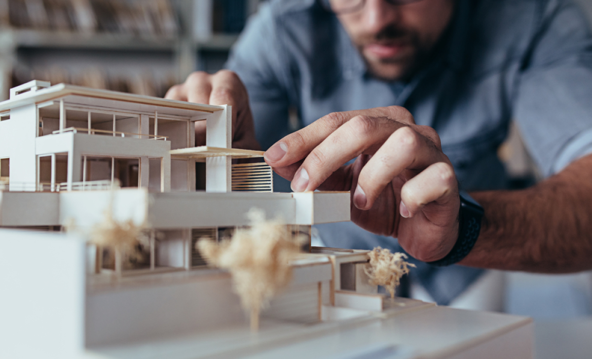 un homme pose la dernière pièce d’une maquette de logement neuf