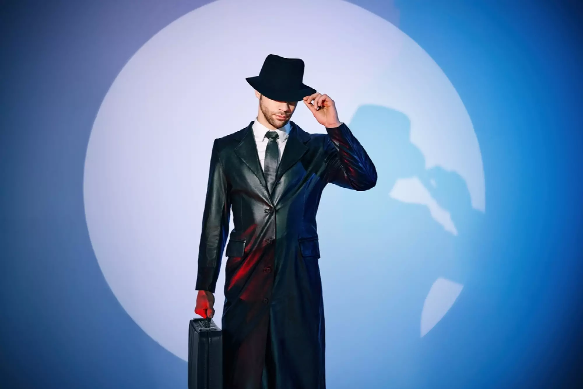 un homme en complet cuir, borsalino et attaché case