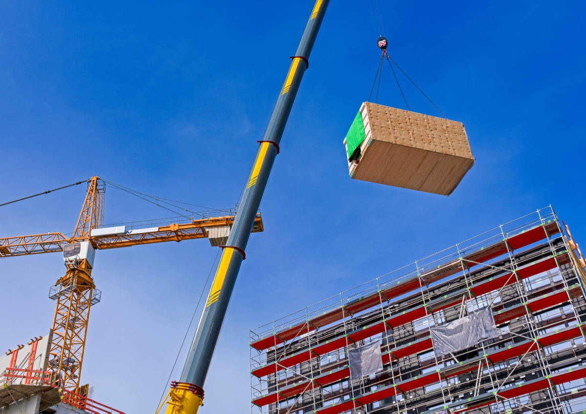 une grue porte un module bois sur un bâtiment de grande hauteur