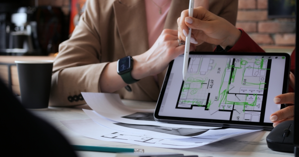 des mains montrant un plan d’architecte sur une tablette numérique
