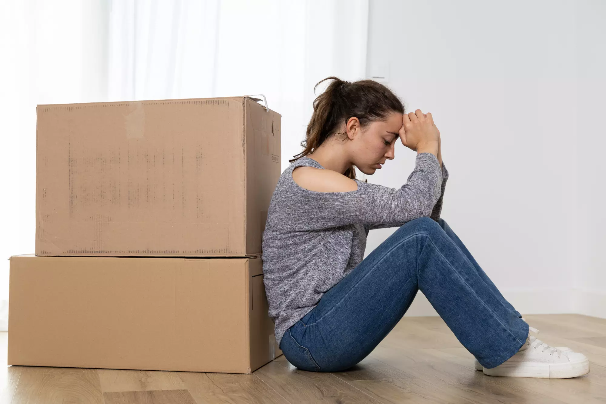 une jeune fille désespérée adossée à ses cartons
